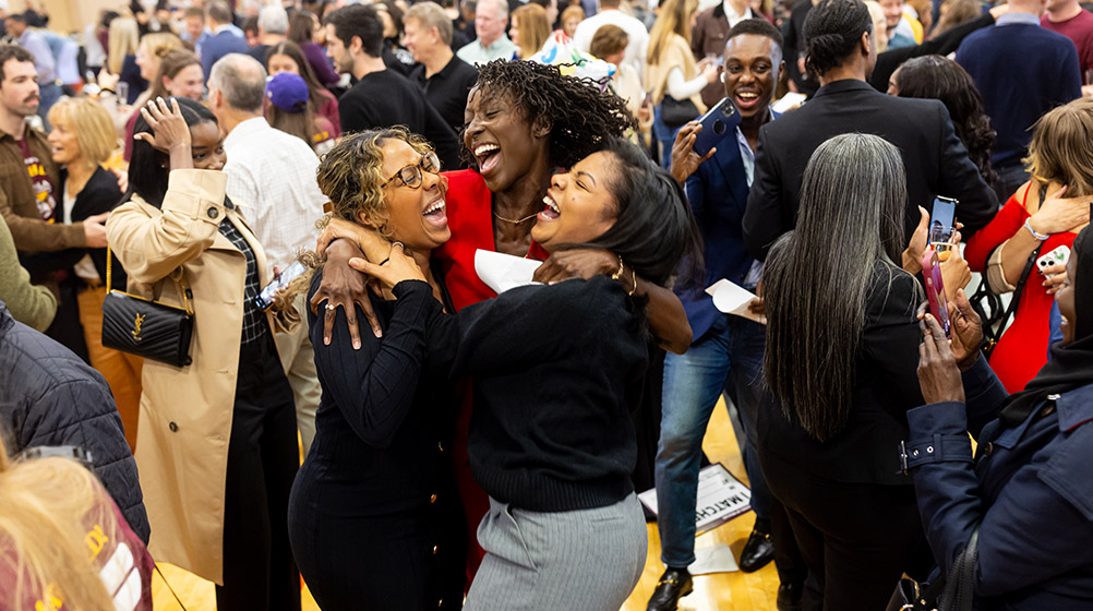 Three students jumping for joy in the middle of the crowd at Match Day